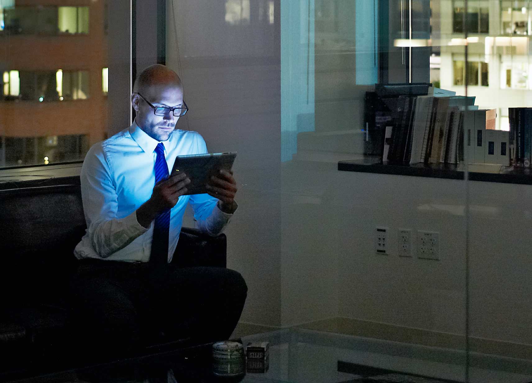 Man in a dark office looking at a tablet computer
